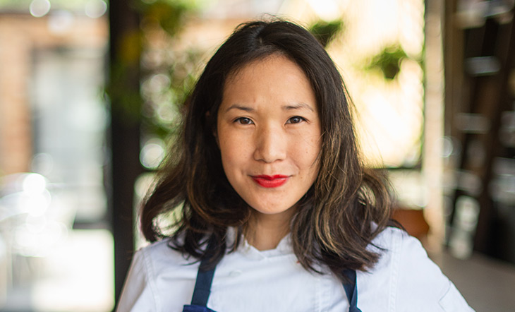 James Beard Award winner Beverly Kim in a white shirt and blue apron photo by Cory Dewald